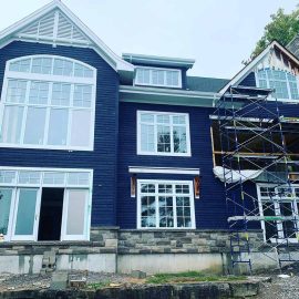 Whitfield Home Improvements - new home construction - lots of light through these large windows; dark blue shiplap siding & stone facade