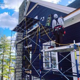 Whitfield Home Improvements - new home construction - dark blue shiplap siding, white trim and stone chimney